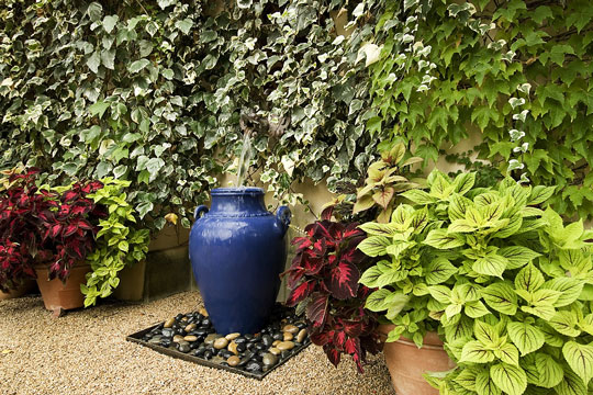 blue urn fountain near garden wall
